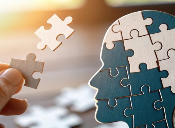 Hand holding puzzle piece to complete brain puzzle